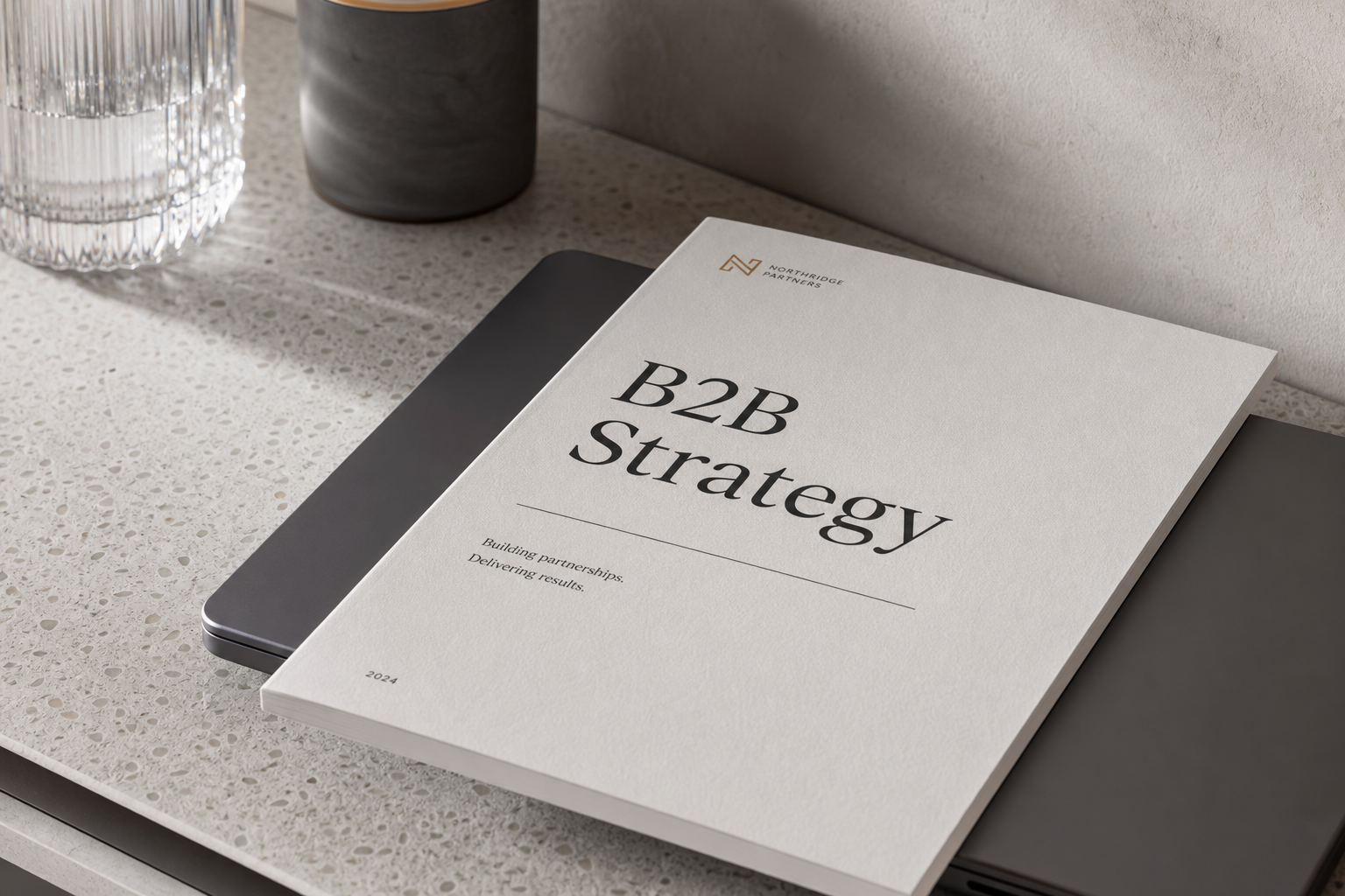 A high-end print document titled B2B Strategy resting on a laptop, developed by a professional B2B lead generation agency