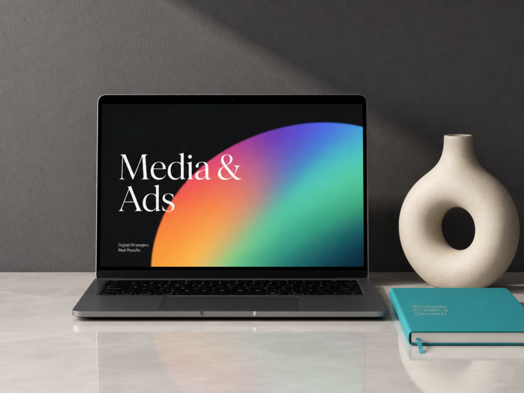 A modern laptop showcasing a clean graphic visualization with Media & Ads on the screen, accompanied by a designer ceramic vase and a turquoise notebook.